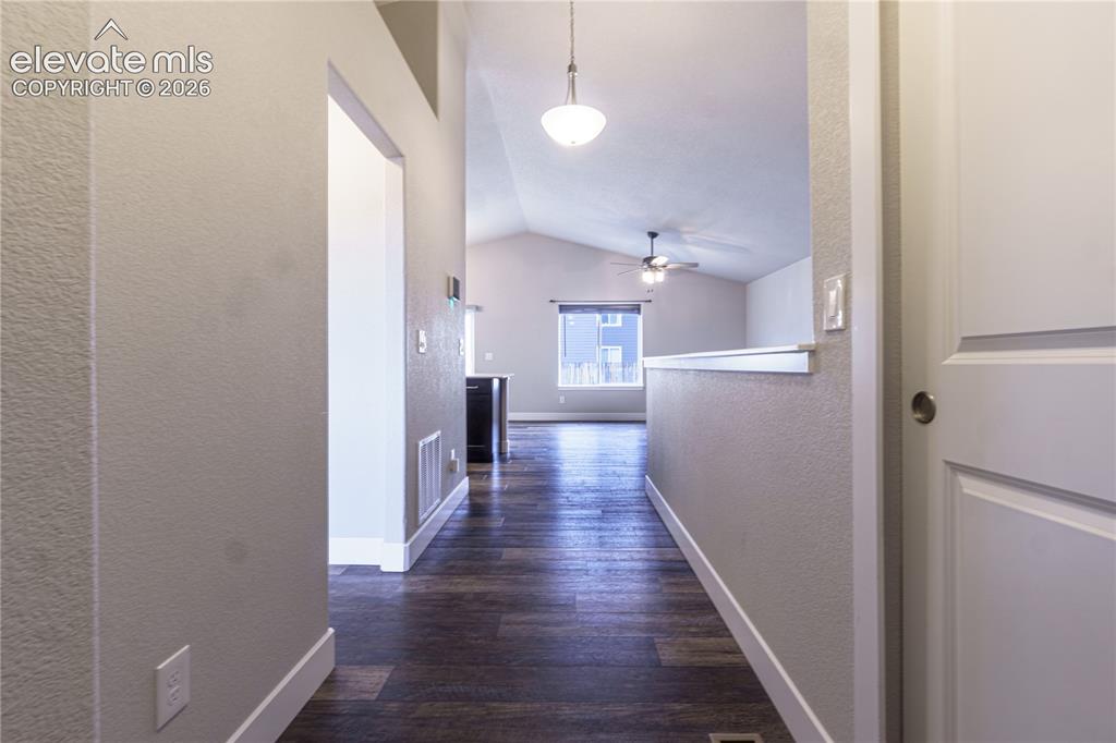 Image 2 of 27: Vaulted ceilings with a ceiling fan, wood-finish flooring, and a half-wall 
