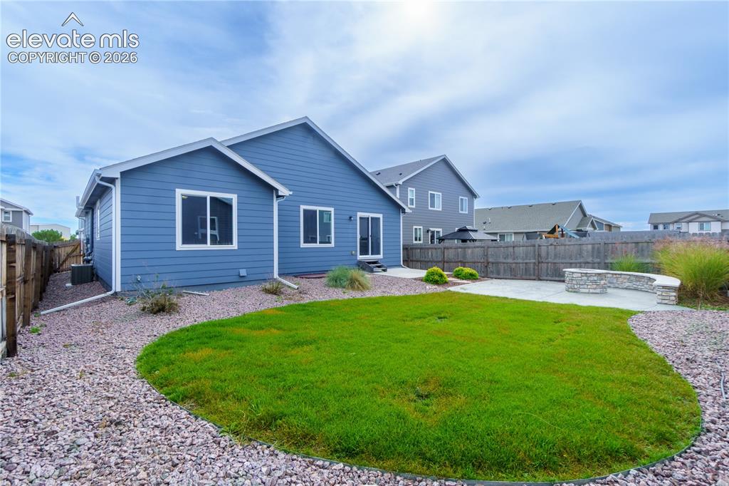 Image 27 of 27: Expansive backyard featuring a manicured lawn, a large concrete patio, and 