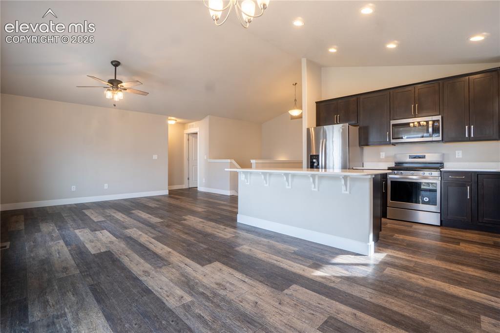 Image 9 of 27: Open-concept living area with wood-finish flooring, a contemporary kitchen 
