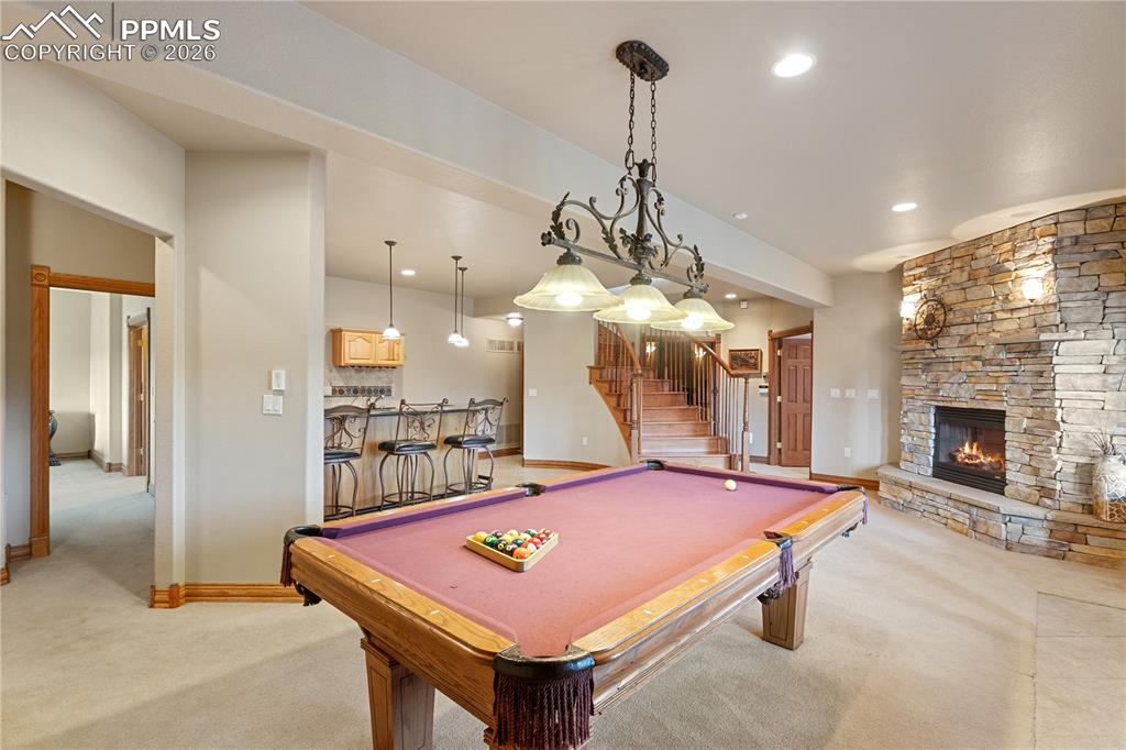 Image 31 of 50: Downstairs game room with fireplace and wet bar. Looking toward gym and the