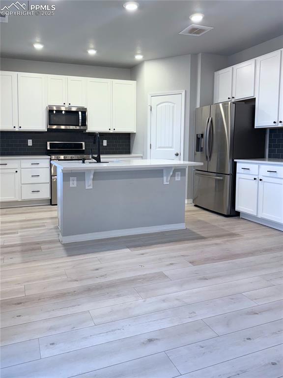 Image 2 of 14: Kitchen featuring decorative backsplash, white cabinets, appliances with st
