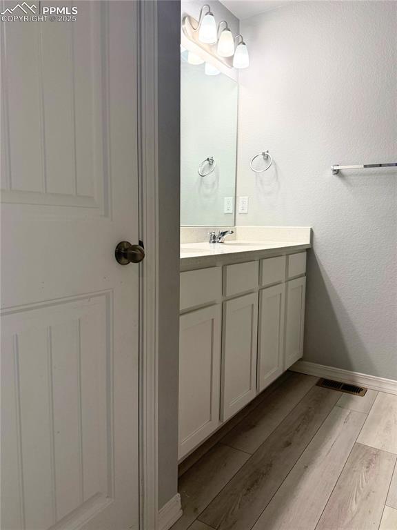 Image 7 of 14: Bathroom with vanity, light wood-style flooring, and a textured wall