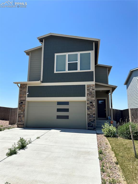 Caption: View of front of home with stone siding, concrete driveway, and an attached garage