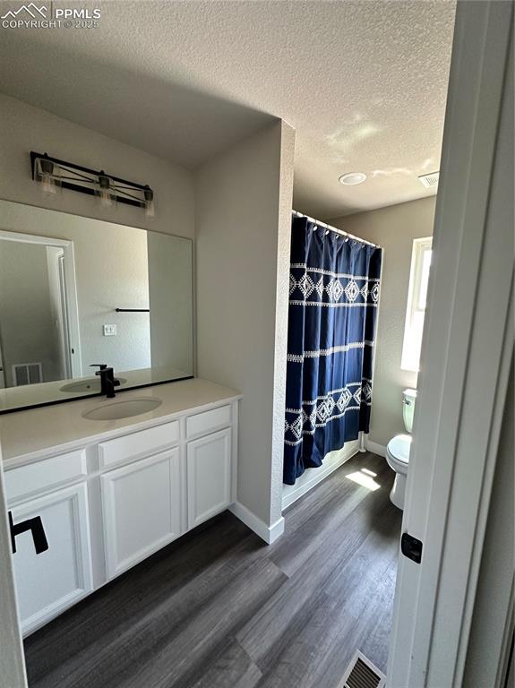 Image 16 of 19: Full bathroom with wood finished floors, vanity, and a textured ceiling