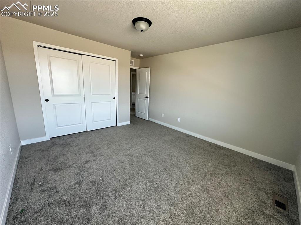 Image 19 of 19: Unfurnished bedroom featuring a closet, carpet floors, and a textured ceili