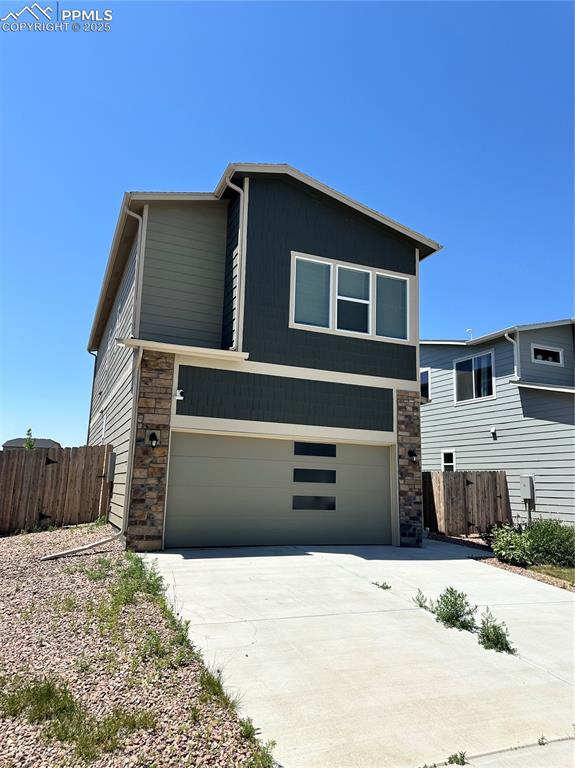 Image 2 of 19: Modern home featuring stone siding, an attached garage, and driveway