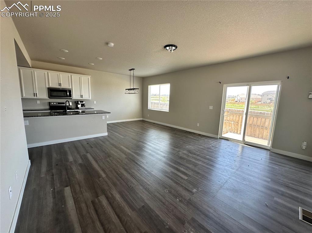 Image 4 of 19: Unfurnished living room with dark wood-style floors, a textured ceiling, an