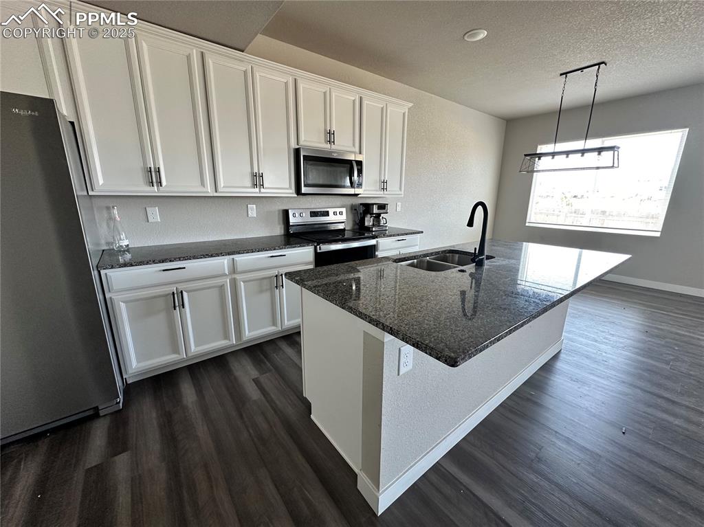 Image 5 of 19: Kitchen with stainless steel appliances, dark wood-style floors, white cabi