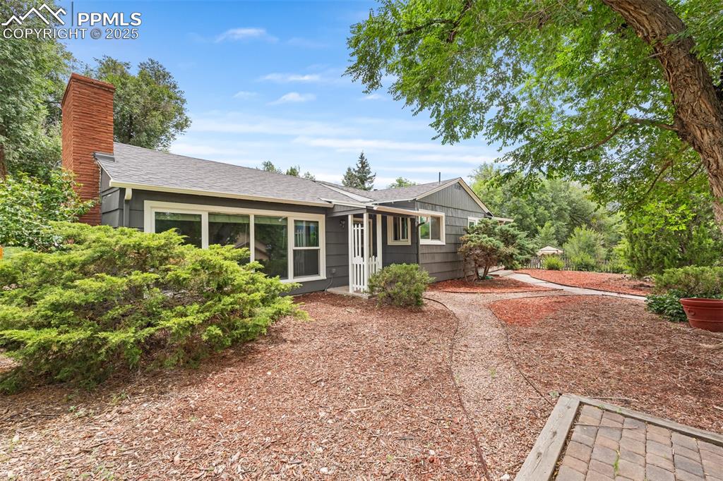 Caption: View of front of home with roof with shingles and a chimney