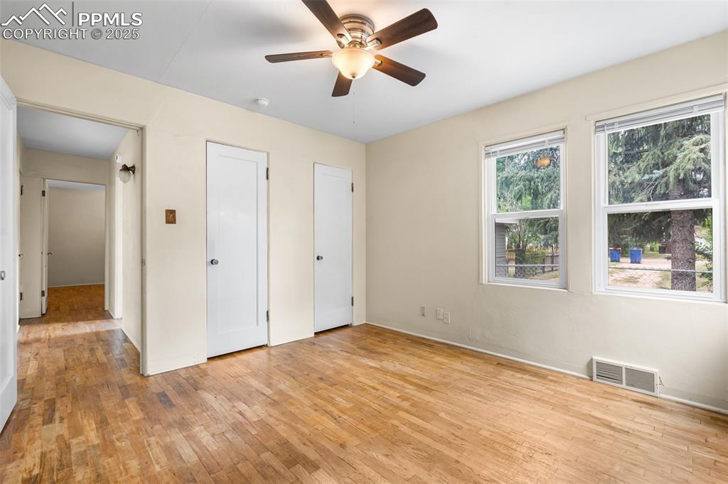 Image 14 of 41: Unfurnished bedroom with light wood-type flooring, a ceiling fan, and two c