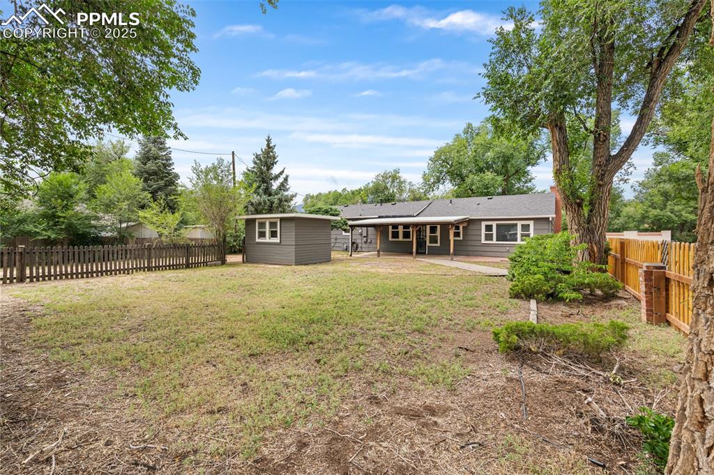Image 26 of 41: Fenced backyard with a patio and an outbuilding
