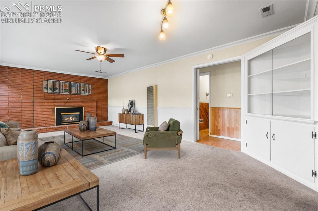 Image 5 of 41: Virtually Staged - Living area with carpet, wainscoting, ceiling fan, crown