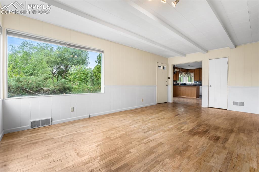 Image 8 of 41: Unfurnished living room with light wood-style floors and beamed ceiling