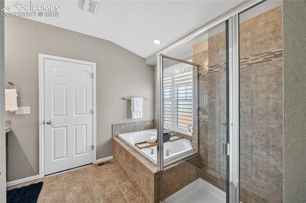 Image 24 of 40: The Primary Bedroom is a spacious retreat with neutral carpet, tray ceiling