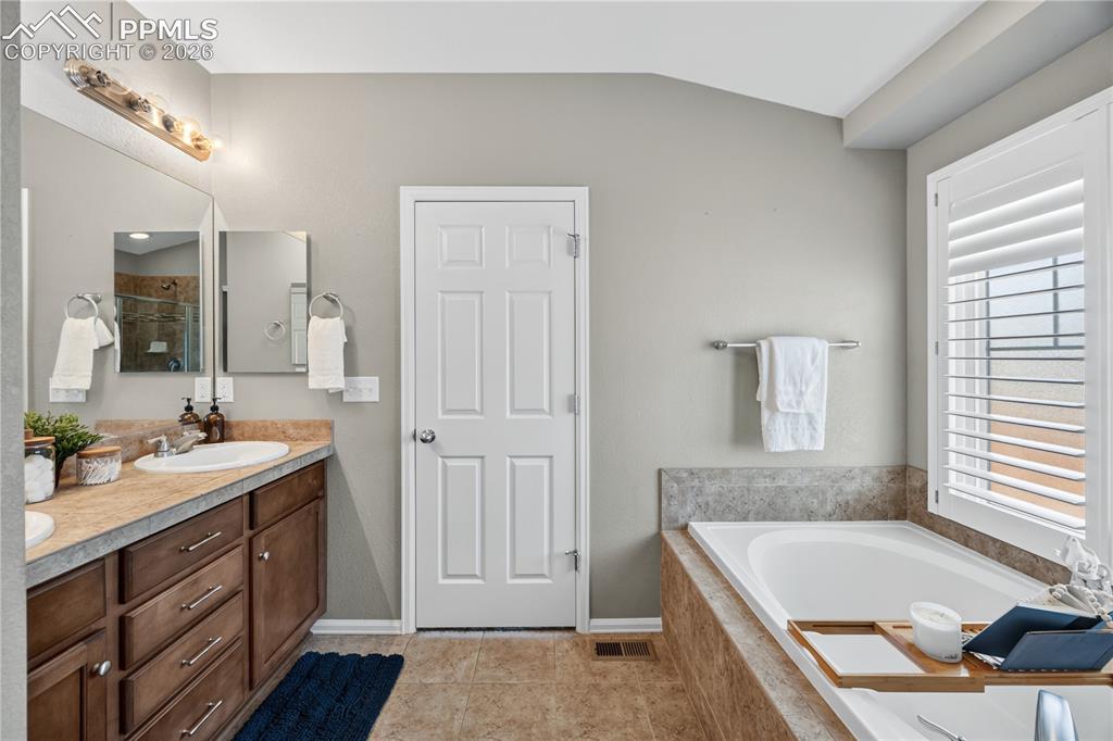 Image 25 of 40: The Primary Bathroom features a tile floor and dual sink vanity with mirror