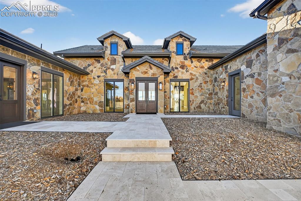Image 14 of 49: Property entrance with stone siding and french doors