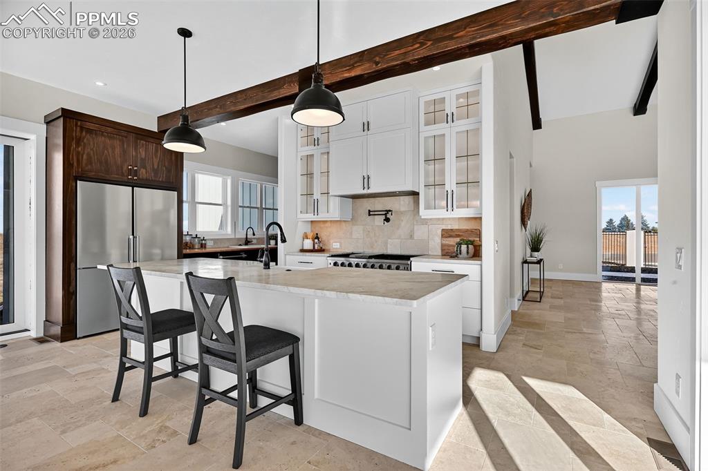 Image 29 of 49: Kitchen featuring freestanding refrigerator, glass insert cabinets, stone t