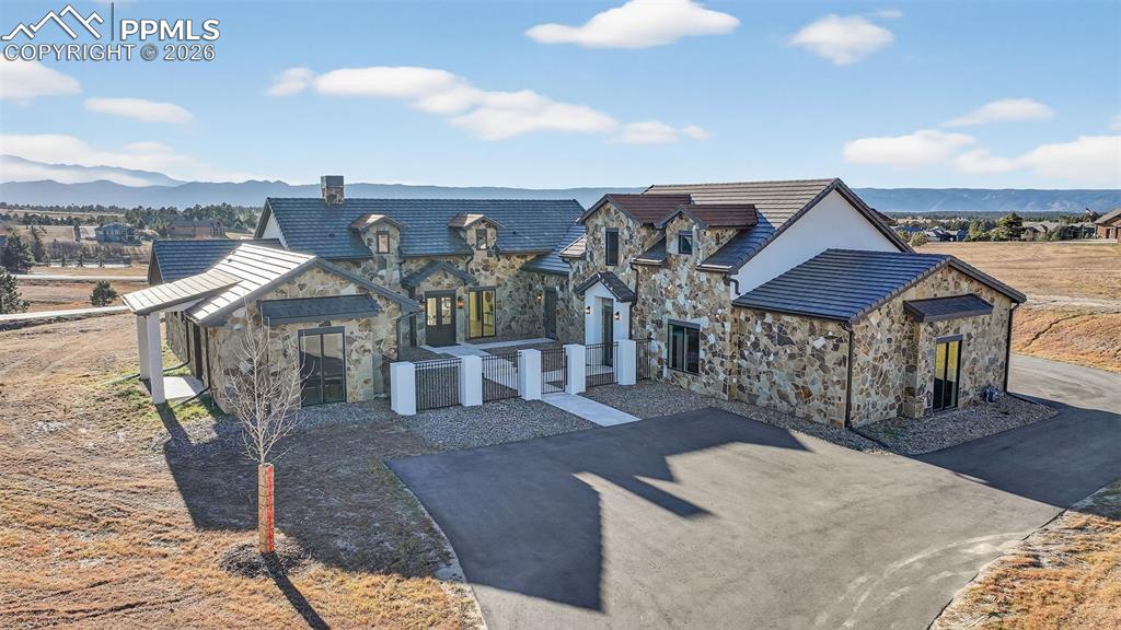 Image 3 of 49: View of front of property featuring stone siding, a mountain view, and a ch
