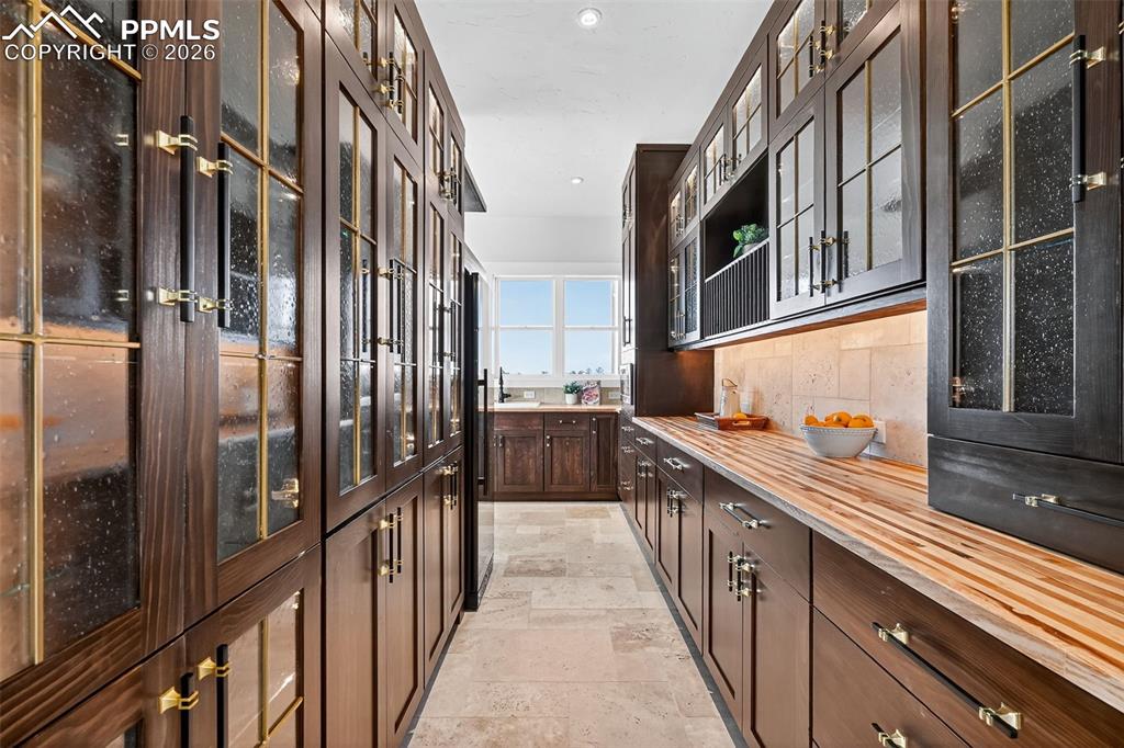 Image 34 of 49: Bar featuring glass insert cabinets, dark wood finish cabinetry, decorative