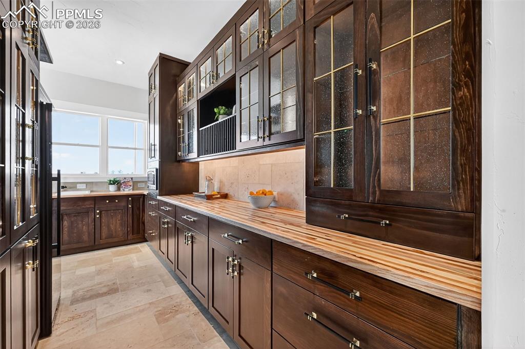 Image 36 of 49: Bar with dark wood finish cabinets, backsplash, wood counters, glass insert