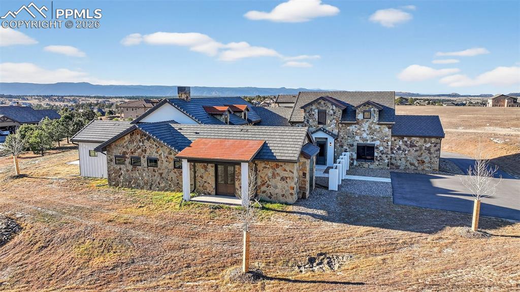 Image 4 of 49: View of front facade with stone siding and a mountain view