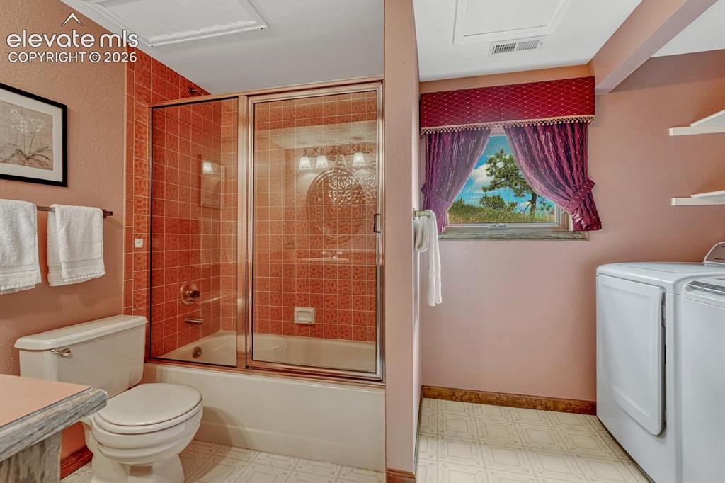 Image 22 of 50: Main Level Bathroom with laundry area including the washer and dryer that s