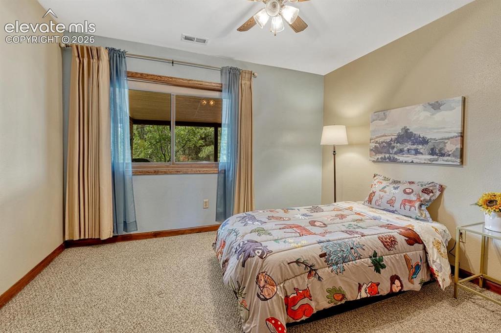 Image 23 of 50: Main level Bedroom with lighted ceiling fan and neutral carpet.