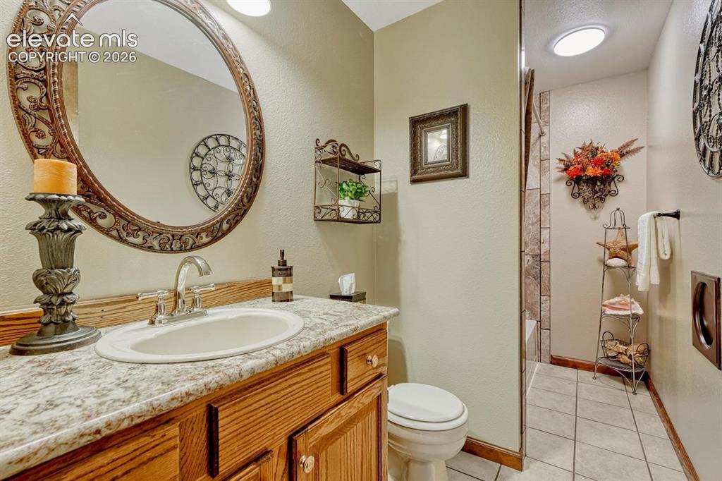 Image 29 of 50: Upper Level Full Bathroom with vanity, mirror, tiled floor, and tiled tub/s