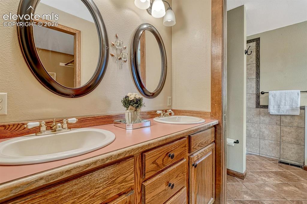 Image 35 of 50: Primary Bathroom with tile floor, dual sink vanity, and mirrors.