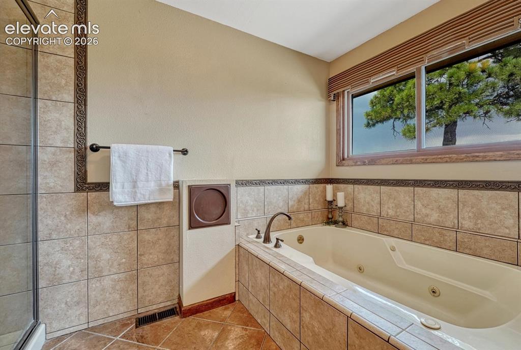 Image 36 of 50: Jetted tub with tile surround in the Primary Bathroom.