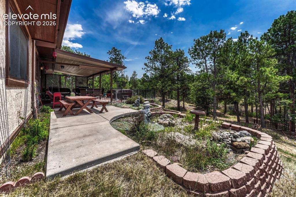 Image 41 of 50: Expanded concrete patio and raised flower bed for the gardening enthusiast.