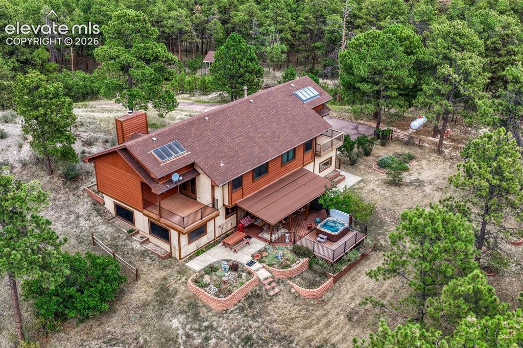 Image 42 of 50: Aerial rear view of home, yard, and surrounding treed lot.