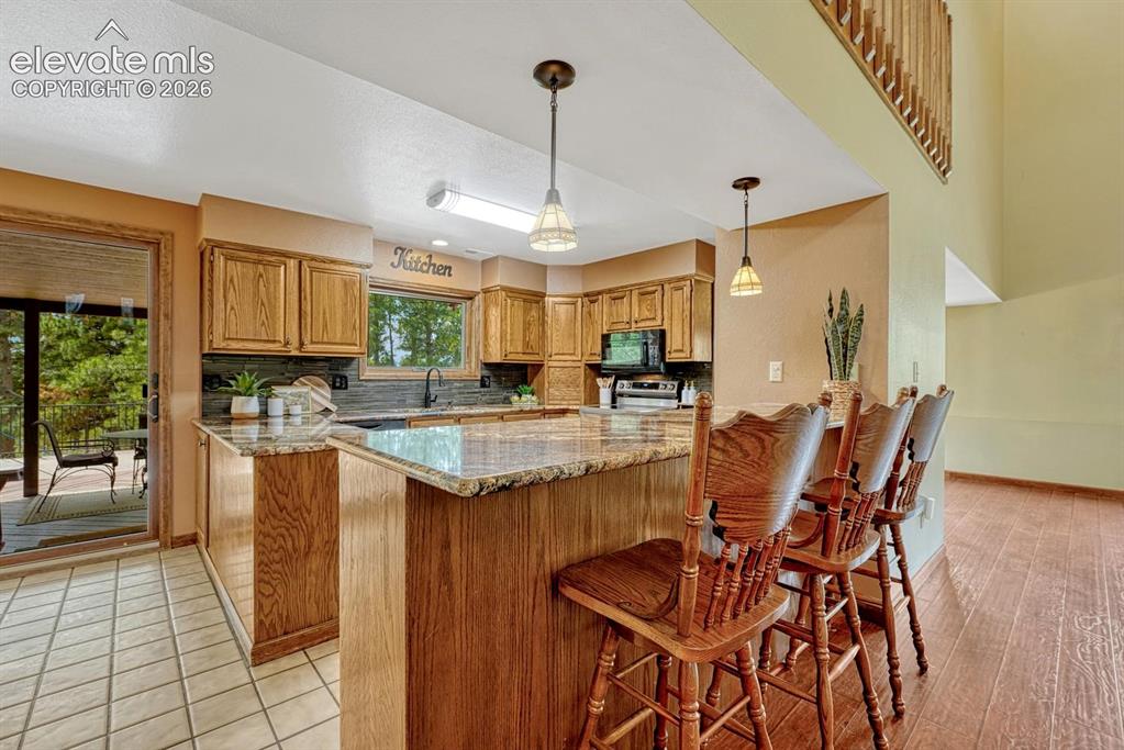 Image 5 of 50: The updated kitchen offers granite countertops, abundant oak cabinetry, pan