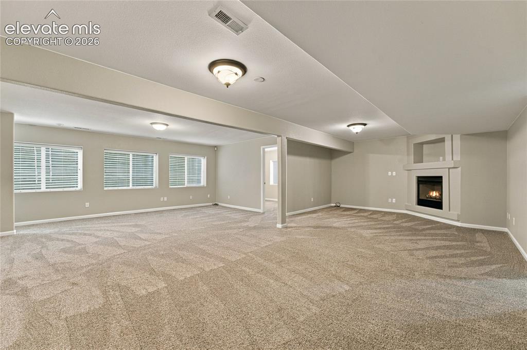 Image 17 of 25: large recreation room in basement with gas fireplace accessing the 3 additi