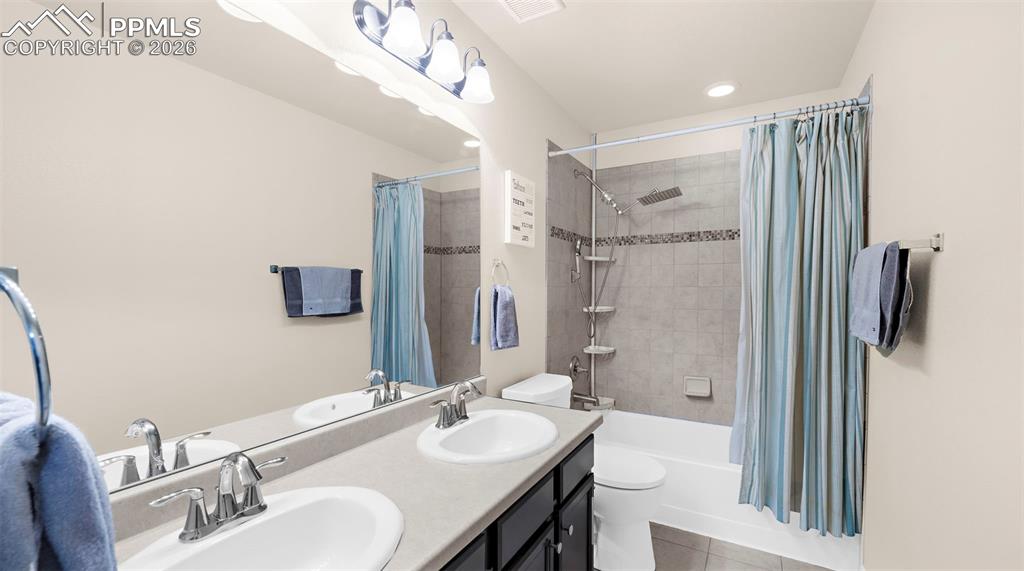 Image 15 of 43: Bathroom with double vanity, shower / bathtub combination with curtain, and