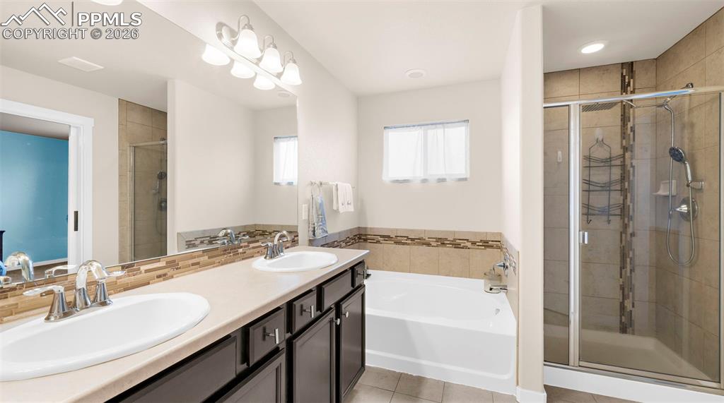 Image 20 of 43: Bathroom with double vanity, a garden tub, a stall shower, and light tile p