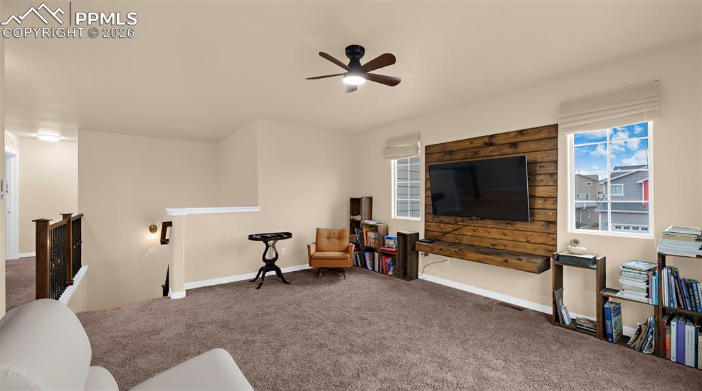 Image 22 of 43: Living area with an upstairs landing, carpet, ceiling fan, and plenty of na