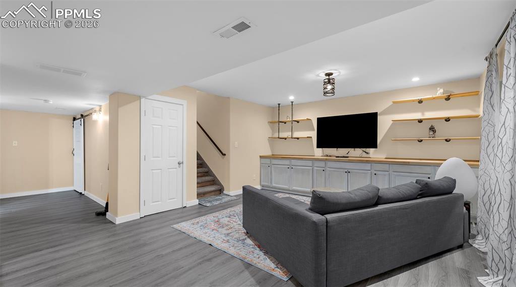 Image 23 of 43: Living room with dark wood-type flooring, recessed lighting, and a barn doo