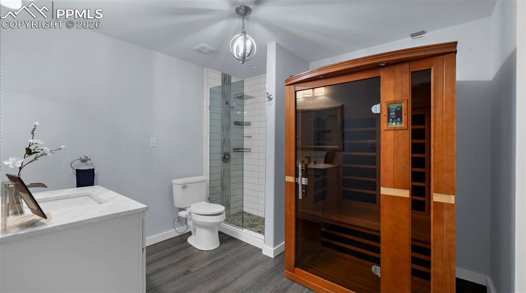 Image 26 of 43: Bathroom with a sauna / steam room, vanity, a shower stall, and dark wood-s