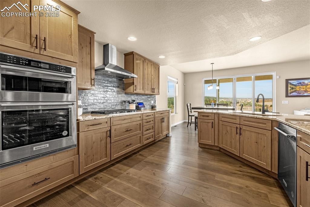 Image 21 of 46: Kitchen with stainless steel appliances, a textured ceiling, decorative bac