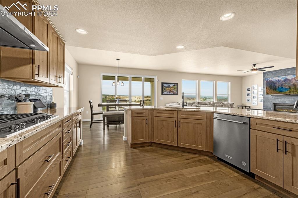 Image 22 of 46: Kitchen with tasteful backsplash, light stone counters, open floor plan, de