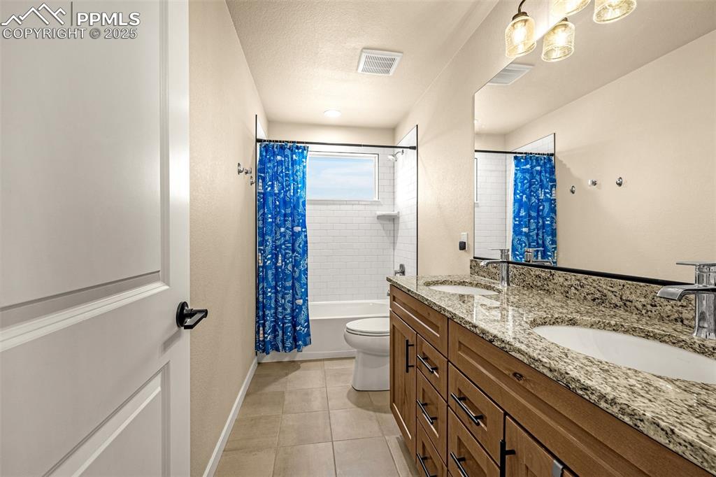 Image 30 of 46: Full bathroom with double vanity, shower / bath combo, and light tile patte