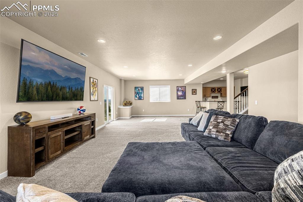 Image 34 of 46: Living area with light carpet, stairway, recessed lighting, and a textured
