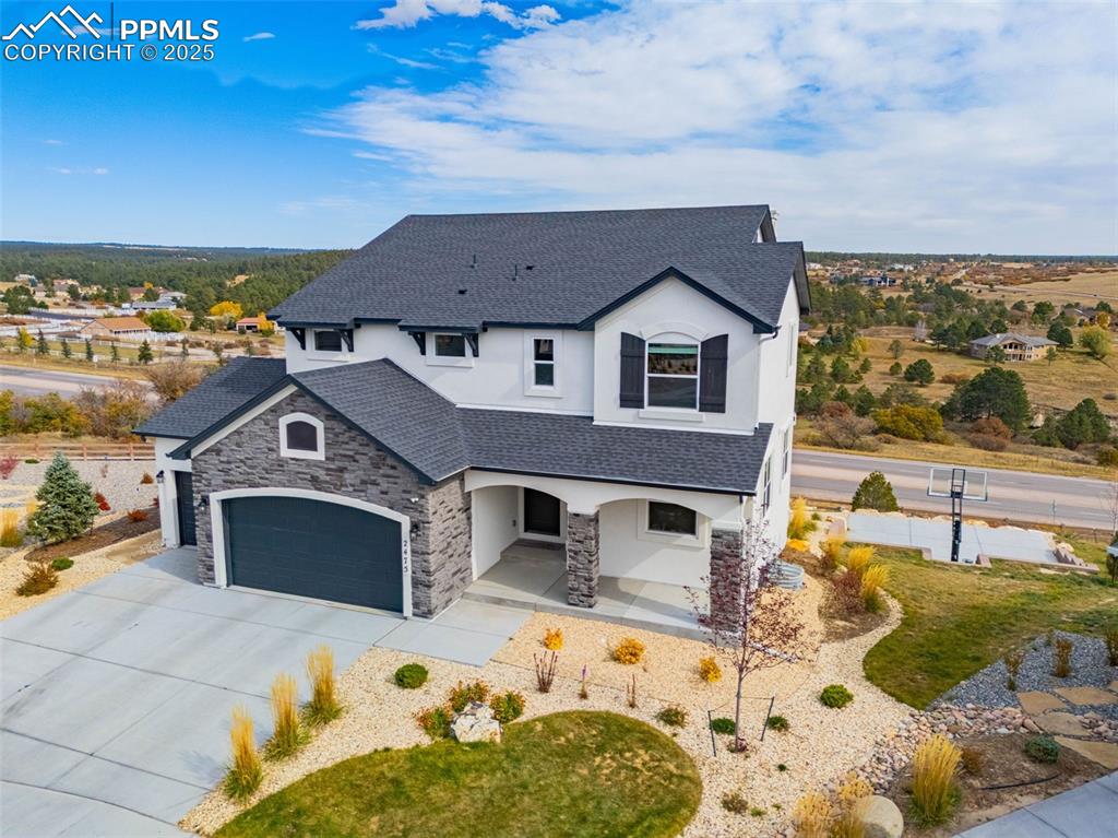Image 38 of 46: View of front of home with stucco siding, stone siding, concrete driveway,