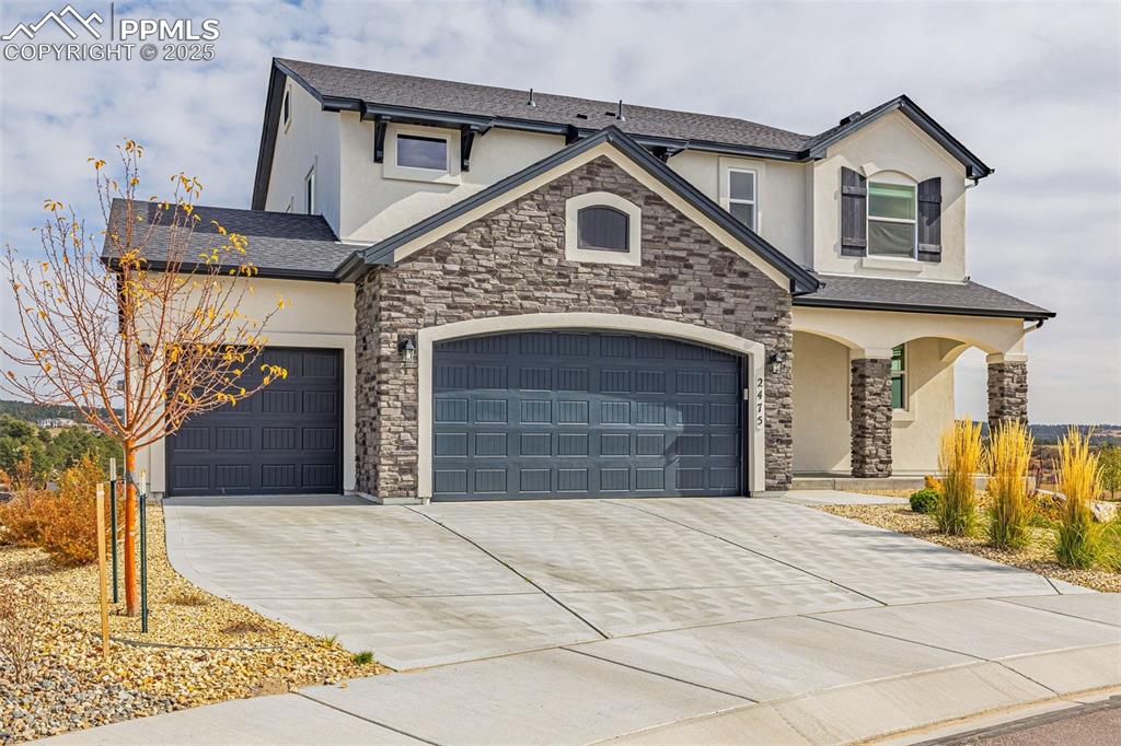 Image 40 of 46: View of front of house featuring stucco siding, stone siding, driveway, and