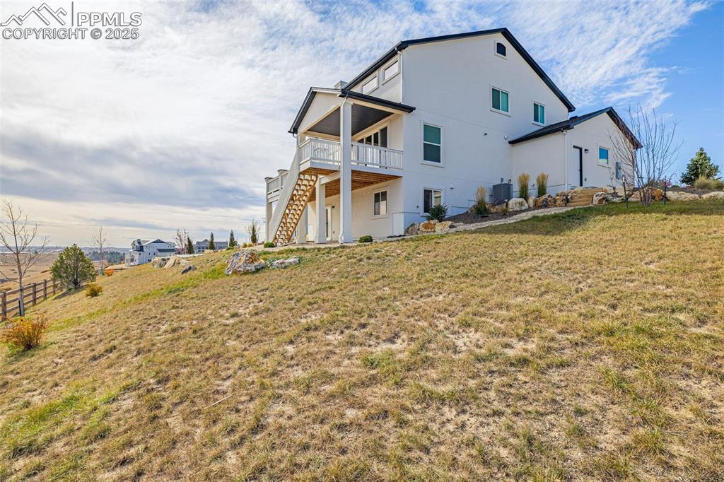 Image 42 of 46: Rear view of house featuring stairs, a lawn, a patio, and stucco siding