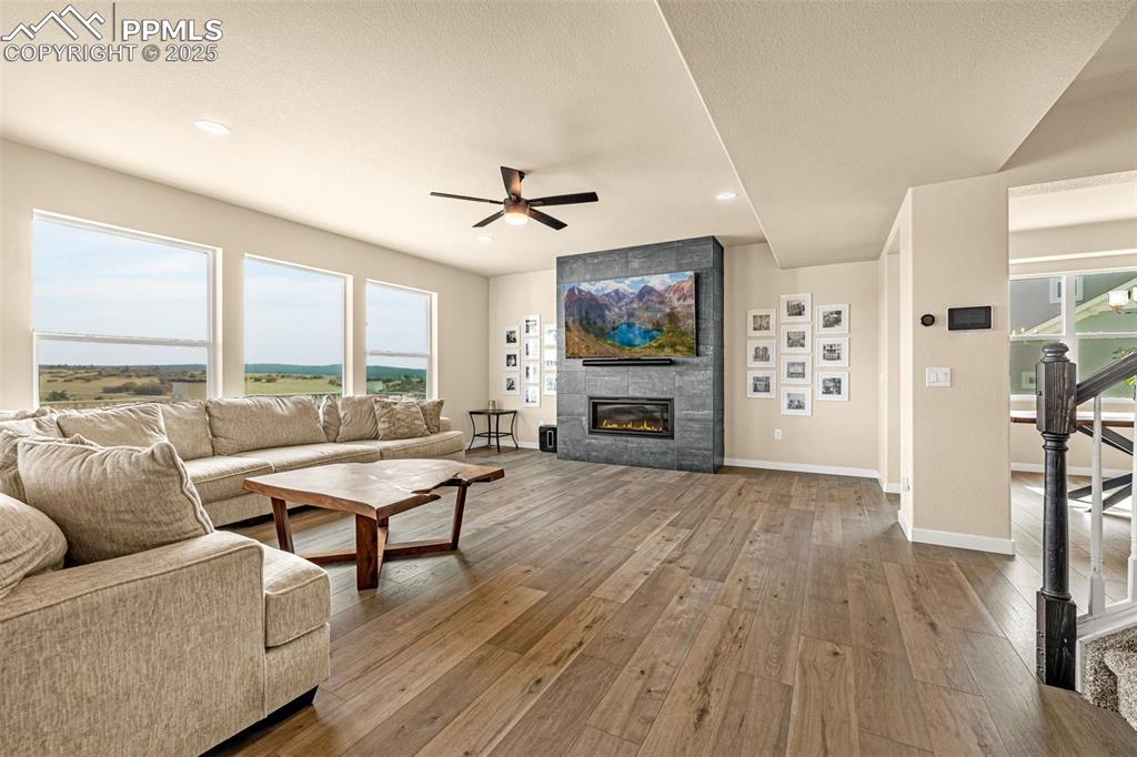 Image 5 of 46: Living area featuring light wood-style flooring, stairway, a tile fireplace