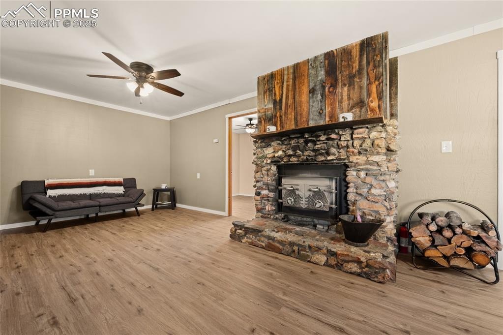 Image 17 of 27: Living room with a ceiling fan, wood finished floors, and ornamental moldin