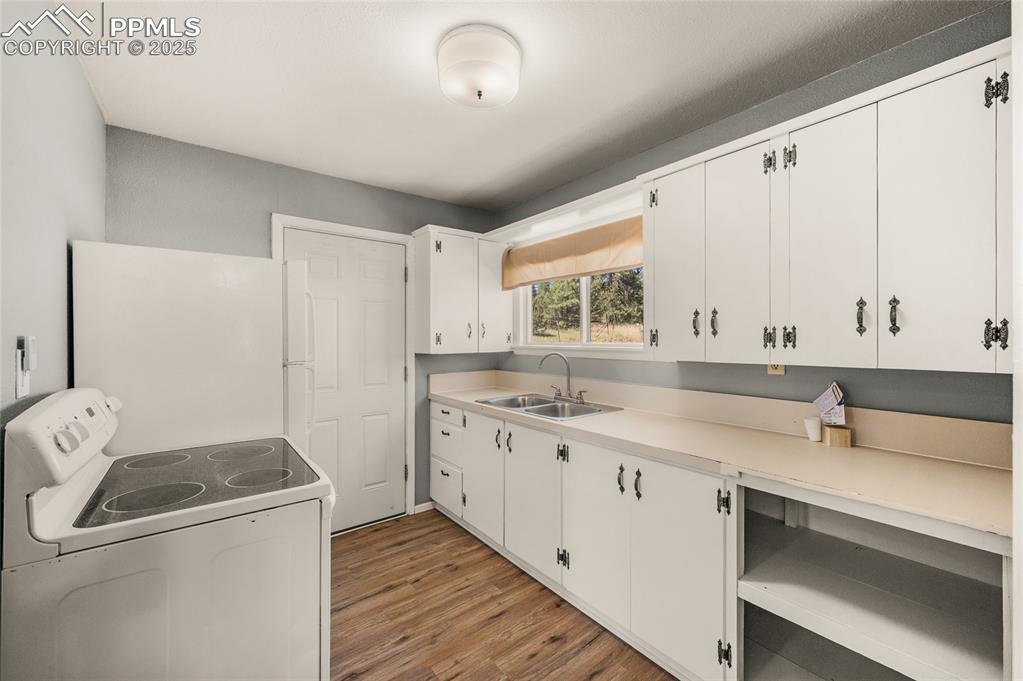 Image 20 of 27: Kitchen featuring white appliances, white cabinetry, light wood-type floori