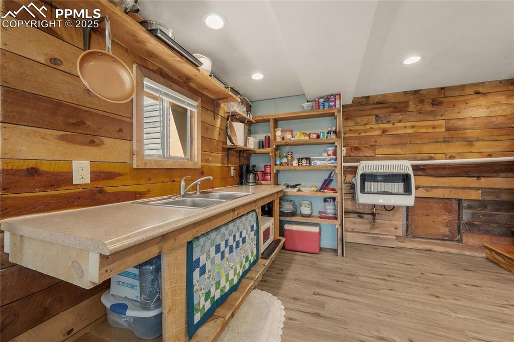 Image 7 of 27: Kitchen featuring heating unit, wooden walls, open shelves, light wood-styl